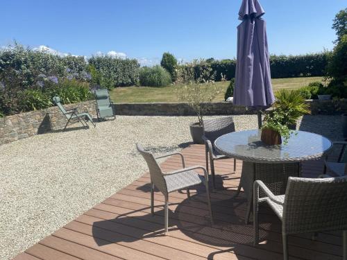 eine Terrasse mit einem Tisch, einem Sonnenschirm und Stühlen in der Unterkunft Holiday Home Cottage du Hamel es Clos by Interhome in Bretteville-sur-Ay