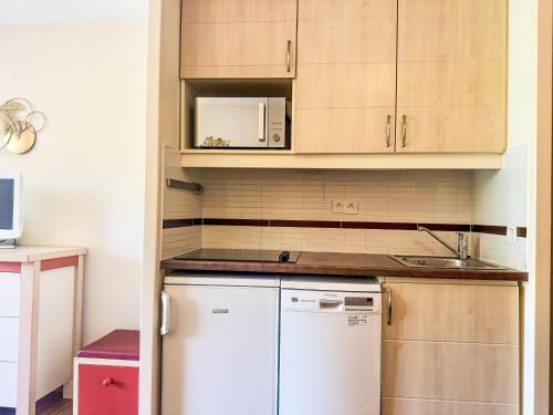 La cuisine est équipée d'un réfrigérateur blanc et d'un four micro-ondes. dans l'établissement Studio Village Cap Estérel - L'Esquinade-101 by Interhome, à Saint-Raphaël