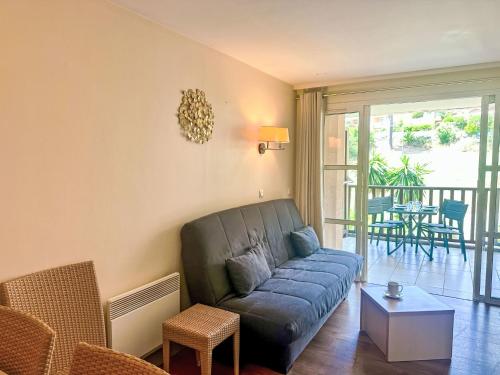un salon avec un canapé bleu et un balcon dans l'établissement Studio Village Cap Estérel - L'Esquinade-101 by Interhome, à Saint-Raphaël