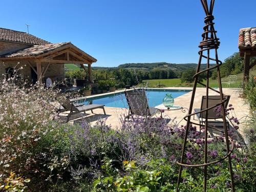 un jardin avec des fleurs violettes et une piscine dans l'établissement La Bastide de La Bogne, à Cordes-sur-Ciel