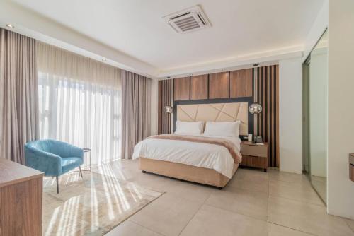 a bedroom with a bed and a blue chair at Villa Reis - The Villa of Kings Hotel & Spa in Bedfordview