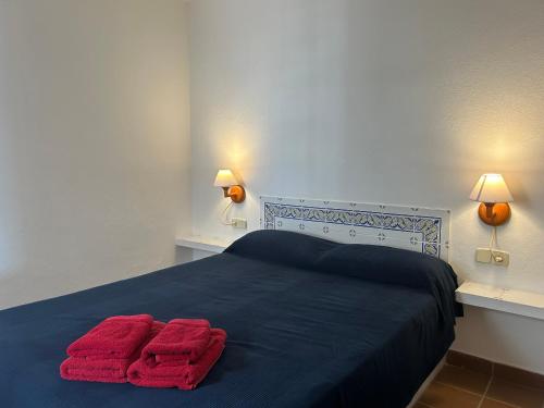 a bedroom with two red towels on a blue bed at ESCOPINYA by SOM Menorca in Fornells