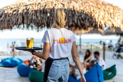 a woman holding a tray with a glass of beer at Villaggio San Francesco - Adria Holiday Mobile Homes in Duna Verde