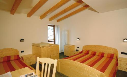 um quarto com 2 camas, uma mesa e cadeiras em Hotel Italia em Baselga di Pinè