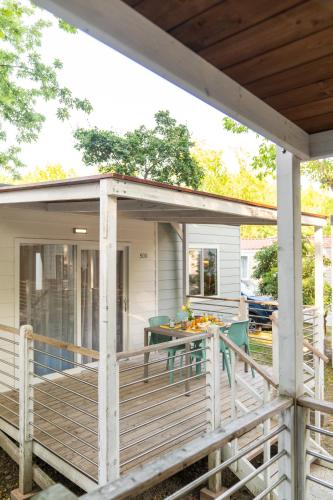 a house with a porch with a table on a deck at Villaggio San Francesco - Adria Holiday Mobile Homes in Duna Verde