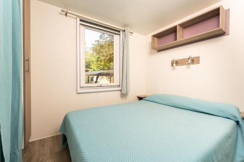 a bedroom with a bed and a window at Villaggio San Francesco - Adria Holiday Mobile Homes in Duna Verde