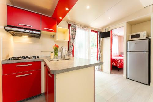 a kitchen with red cabinets and a white refrigerator at Villaggio San Francesco - Adria Holiday Mobile Homes in Duna Verde