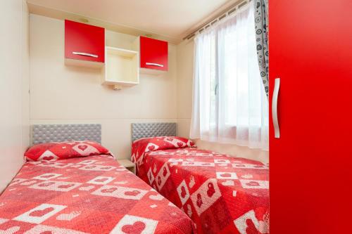 two beds in a room with red at Villaggio San Francesco - Adria Holiday Mobile Homes in Duna Verde
