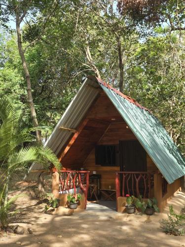 a cabin with a blue roof in the woods at Relax Nature Villa in Sigiriya