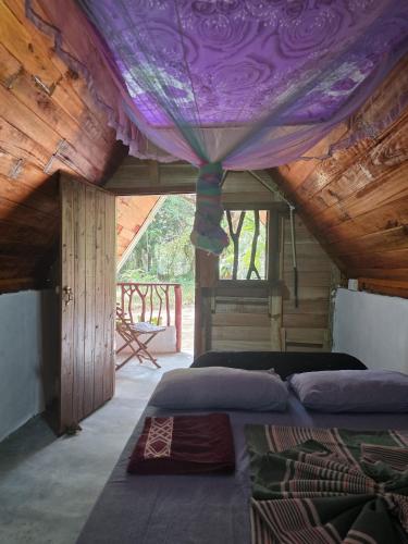 a bedroom with two beds and a purple canopy at Relax Nature Villa in Sigiriya
