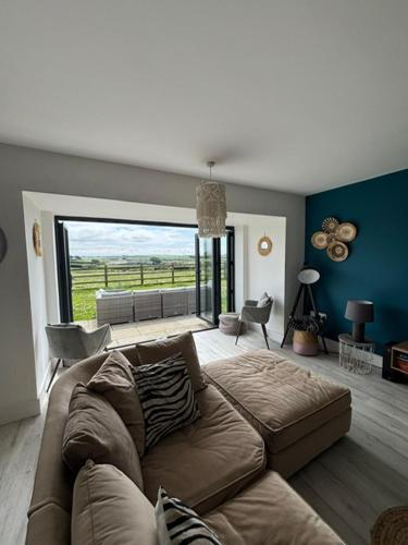 a living room with a couch and a large window at Anglesey sleeps 10 with hot tub at an additional cost in Llanfaelog