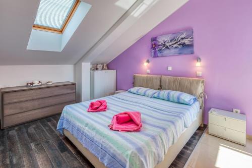 a bedroom with purple walls and a bed with two pink bags on it at Apartment Roberto in Njivice