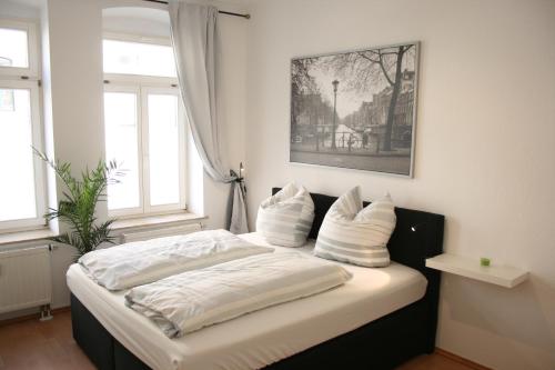 Schlafzimmer mit einem Bett mit weißer Bettwäsche und Kissen in der Unterkunft Citywohnungen Halle Saale in Halle an der Saale