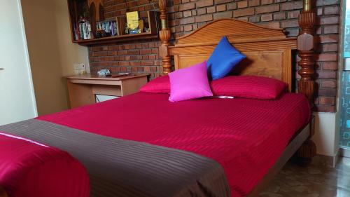 a bed with pink and blue pillows in a room at Gardenlife in Sri Jayewardenepura Kotte