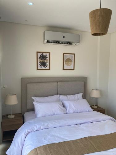 a bedroom with a large bed with white sheets at First Row to Pyramids 2BDR Apt in Kafrat Naşşār