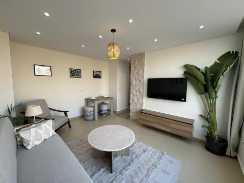 a living room with a couch and a tv at First Row to Pyramids 2BDR Apt in Kafrat Naşşār