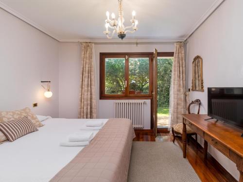 a bedroom with a bed and a television and a window at Preciosa y amplia casa con piscina in Liendo