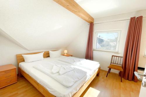 a bedroom with a large white bed with a window at Am Waldwinkel Ferienhaus Sonne in Koserow