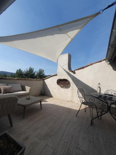 a patio with a table and chairs and a couch at Maison Grand Rue - Vue Exceptionnelle sur le Luberon in Lauris