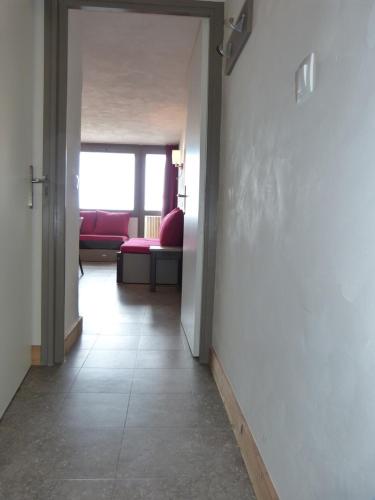 - un couloir avec un salon doté d'un canapé rouge dans l'établissement travelski home select - Vue Mont Blanc, à Aime La Plagne