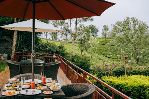 een tafel met borden en een paraplu bij Green Nest Resort Ooty in Kotagiri