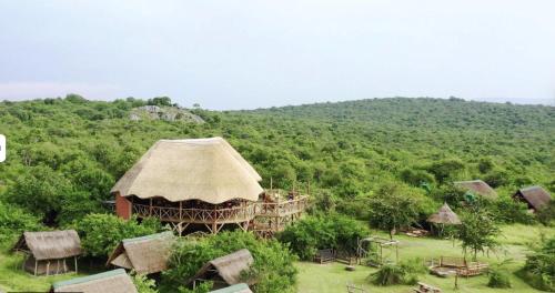 a group of huts in a field with a mountain at Leopard Rest Camp in Mbarara