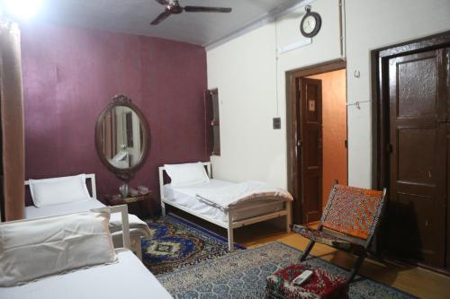 a room with two beds and a mirror and a chair at Vedic Dham Ganga in Rishīkesh