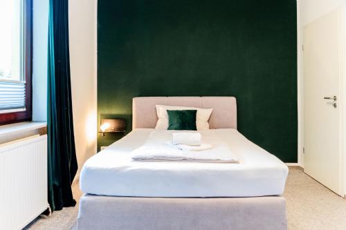 a bedroom with a white bed with a green wall at S17 Bude 8 Studio in Flensburg
