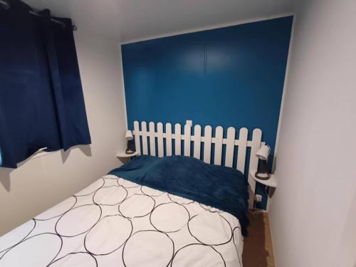 Un dormitorio con una cama con una pared azul. en MOBIL HOME le WELCOM, en Valras-Plage
