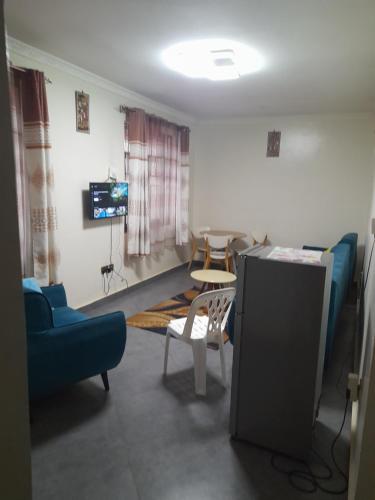 a living room with blue chairs and a tv at City View Apartment, Albert Cook Road in Kampala