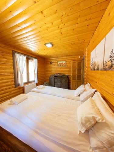 a bedroom with two beds in a wooden cabin at Casa Valea Râului Vârciorog in Vîrciorog