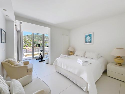 une chambre blanche avec un lit et une chaise dans l'établissement Penthouse 2-Bedroom apartment with 360º views and parking, à Cannes