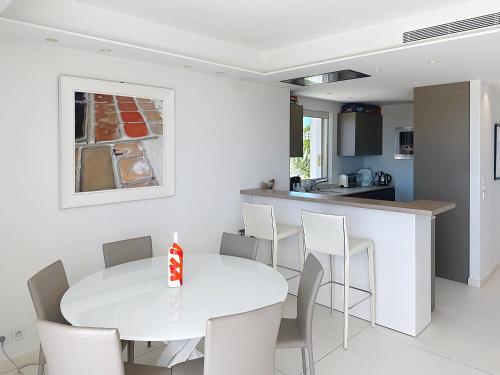 une cuisine et une salle à manger avec une table et des chaises blanches dans l'établissement Penthouse 2-Bedroom apartment with 360º views and parking, à Cannes