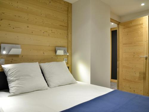 - une chambre avec un lit blanc et un mur en bois dans l'établissement Appartement rénové aux Coches, proche pistes, 5 pers, terrasse, parking gratuit, animaux admis - FR-1-181-1981, à La Plagne Tarentaise