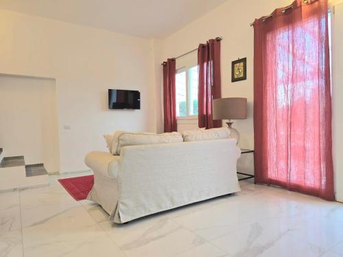 a living room with a white couch and red curtains at Tenuta Feraxi - Private Paradise in San Priamo