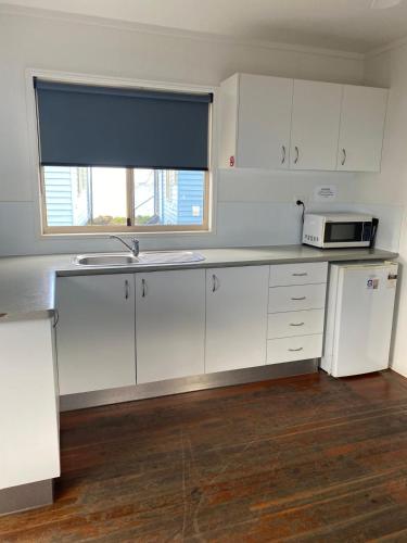 a kitchen with white cabinets and a sink and a window at Absolute Oceanfront Tourist Park in Bargara