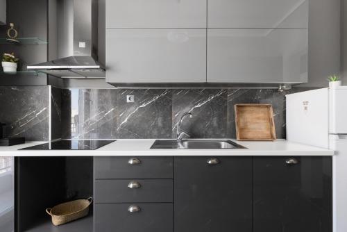 a kitchen with black and white cabinets and a sink at Houseloft Cityscape Bliss in Thessaloniki