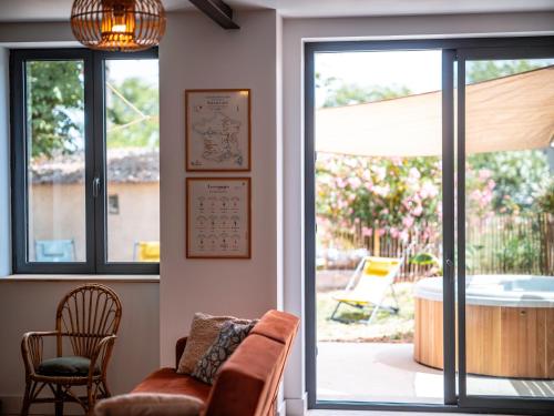 a living room with a chair and a glass door at Gîte des Roussèles - Climatisation, Spa, jardin in Gaillac