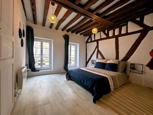 a bedroom with a bed in a room with wooden ceilings at La Trame Bourguignonne - Centre ville in Auxerre