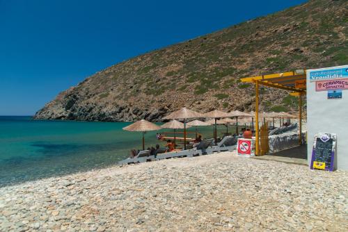 a group of people sitting on a beach with umbrellas at Green Bay Studio 2 in Sifnos