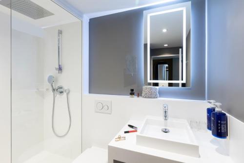 a bathroom with a sink and a mirror at Novotel Luxembourg Kirchberg in Luxembourg