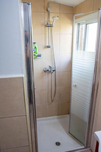 a shower with a glass door in a bathroom at Noa's wooden cabin in Sha'al