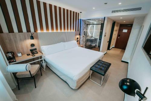 a bedroom with a large white bed and a desk at Felix Hotel in Valls