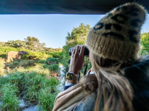 a woman taking a picture of an elephant from a vehicle at AfriCamps at Bonamanzi Game Reserve in Hluhluwe