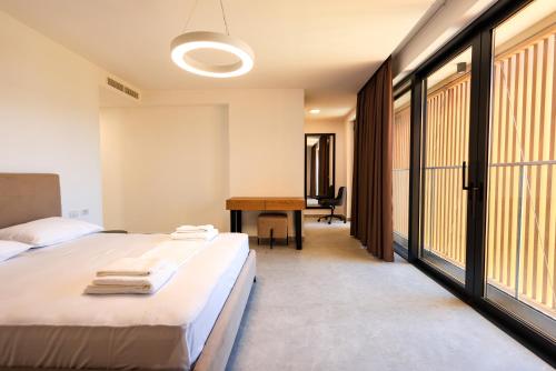 a bedroom with a bed and a desk and windows at SanPietro Premium Villas in Draçi