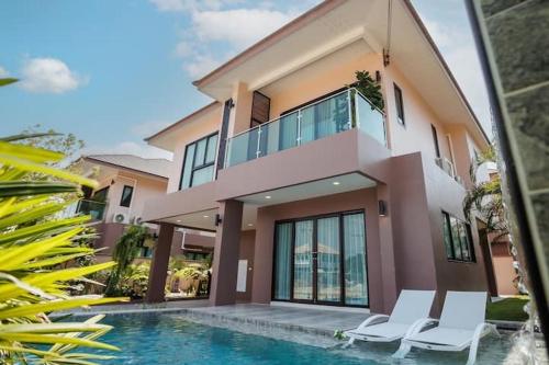 a house with a swimming pool and two white chairs at 超值优选 新房特惠 独栋泳池花园别墅 15分钟到海边 in Ban Huai Yai
