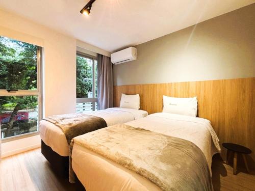 two beds in a room with a window at UniHome Niterói by Housi in Niterói