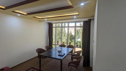 a dining room with a table and chairs and a large window at Alpine Resort Khaplu in Khaplu