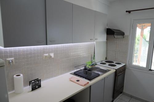 a white kitchen with a stove and a sink at Kritharistra Home in Vlakhiá