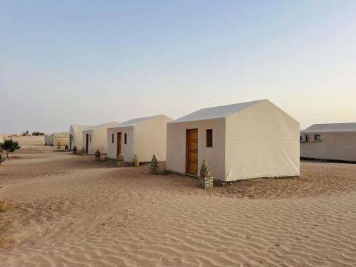 a row of white tents in the desert at Camp Dunes Insolites Sabria in Sabria